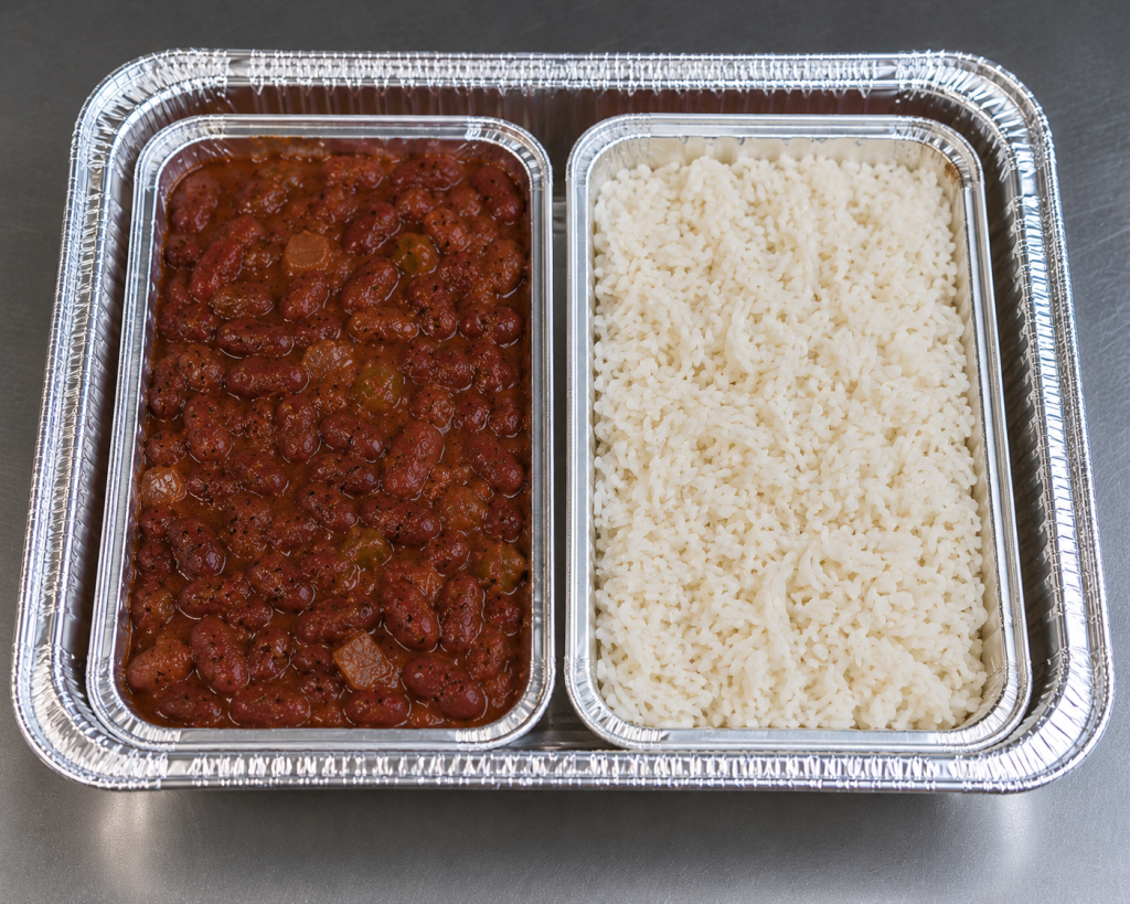Half-size aluminum catering tray containing separate portions of Cajun red beans and white rice in individual containers for catering service.