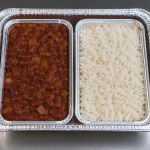 Half-size aluminum catering tray containing separate portions of Cajun red beans and white rice in individual containers for catering service.