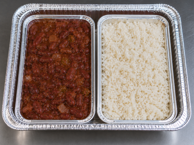 Half-size aluminum catering tray containing separate portions of Cajun red beans and white rice in individual containers for catering service.